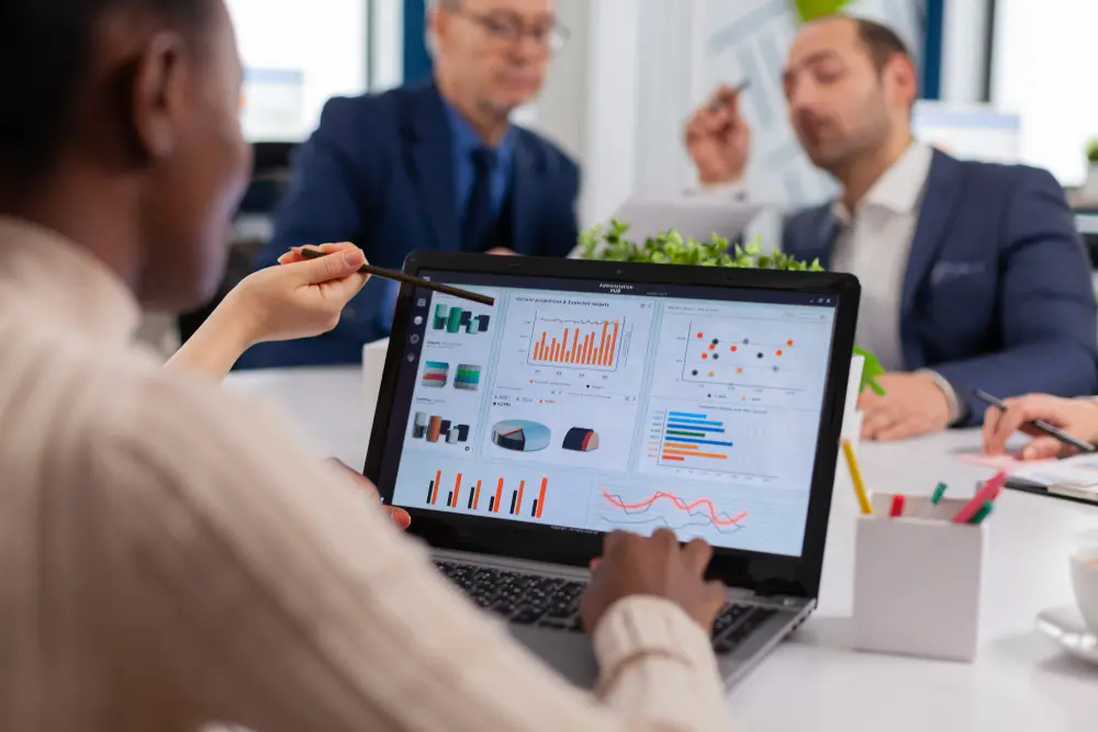 Analista señalando indicadores logísticos en pantalla durante revisión de desempeño operativo con equipo