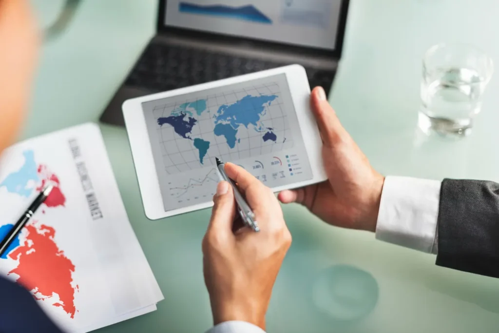 Manos sosteniendo tablet con mapa mundial con rutas que representan el transporte internacional y la logística global