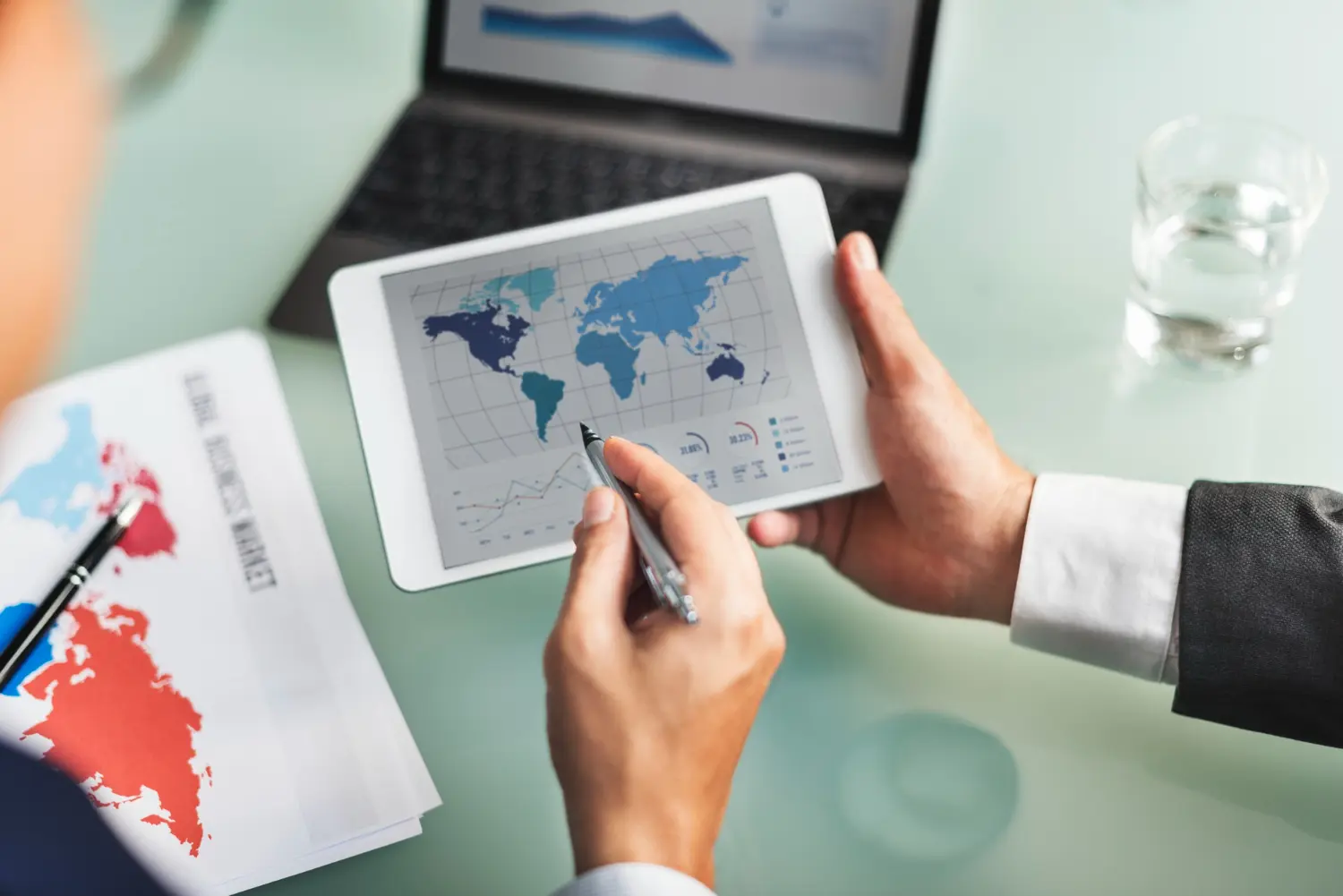 Manos sosteniendo tablet con mapa mundial con rutas que representan el transporte internacional y la logística global